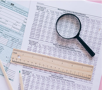 Formularios de impuestos con lupa y lápices